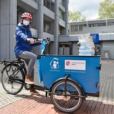 Das Bild zeigt eine Frau auf einem Lastenfahrrad