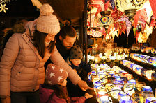 Eine Familie schaut an einem Stand bunte Lampen an.