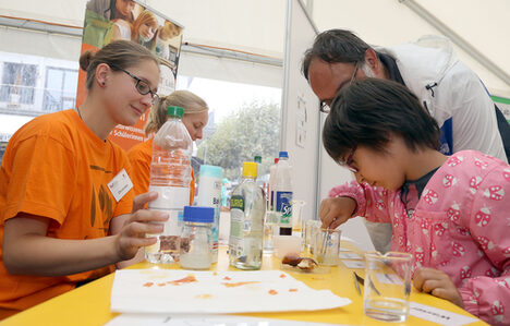 Ein Mädchen mit Pinzette an einem Stand des Wissenschaftsmarktes